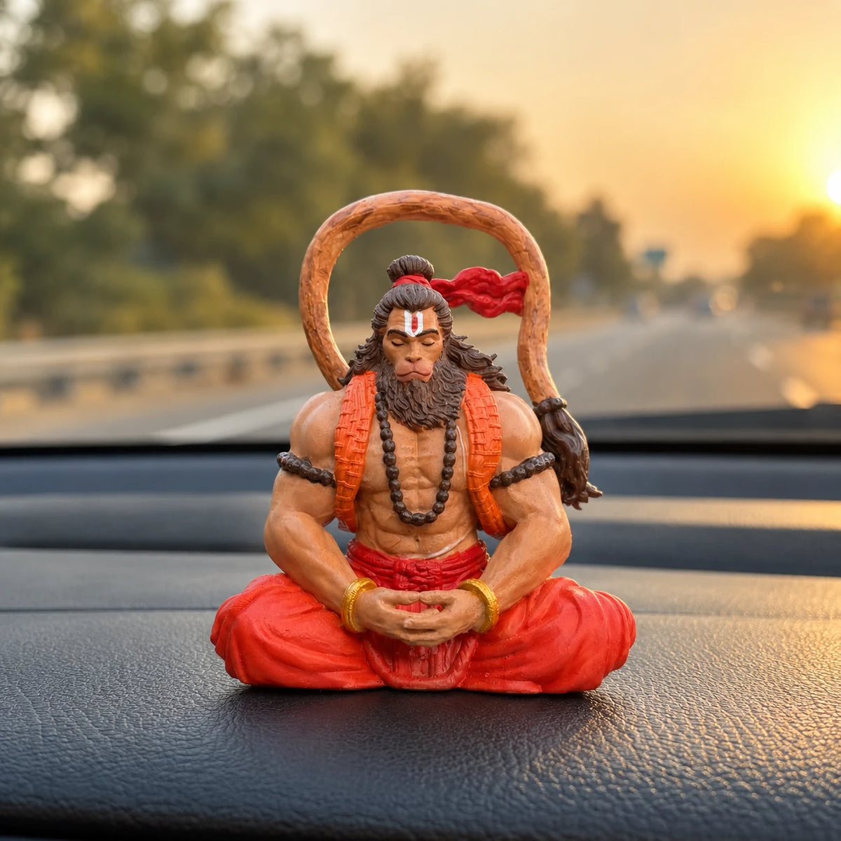 Ram Bhakt Hanuman Ji idol placed on a car dashboard at sunset