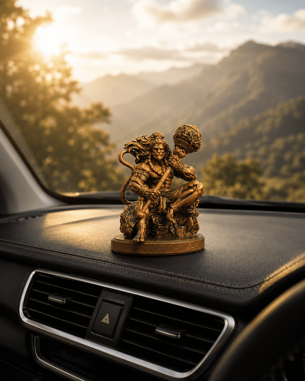 The Mahabali Hanuman idol on a dashboard with hills beyond the windscreen