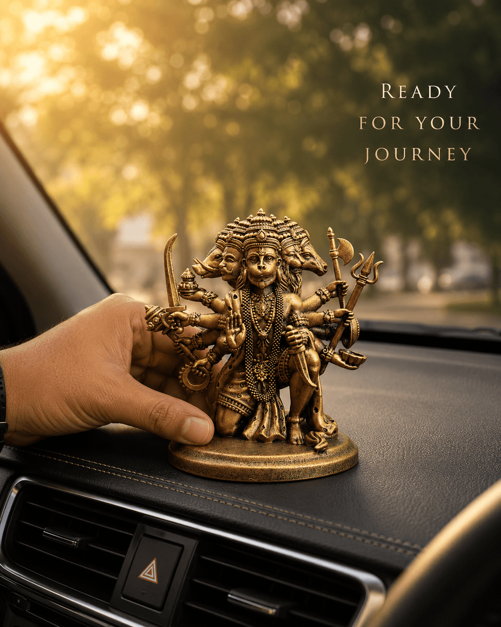 A hand placing the Panchmukhi Hanuman idol on a car dashboard