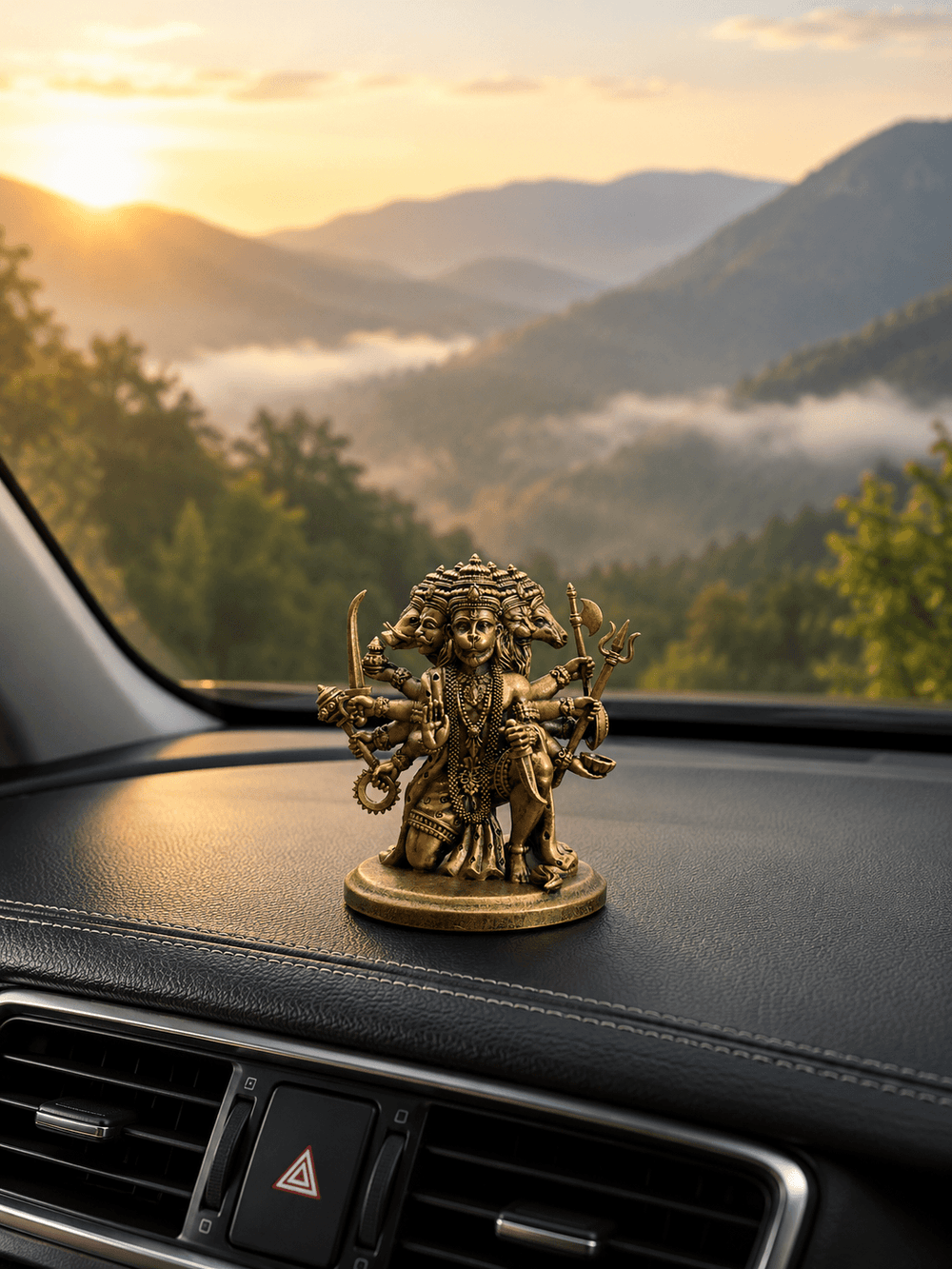 The Panchmukhi Hanuman idol on a dashboard with hills beyond the windscreen