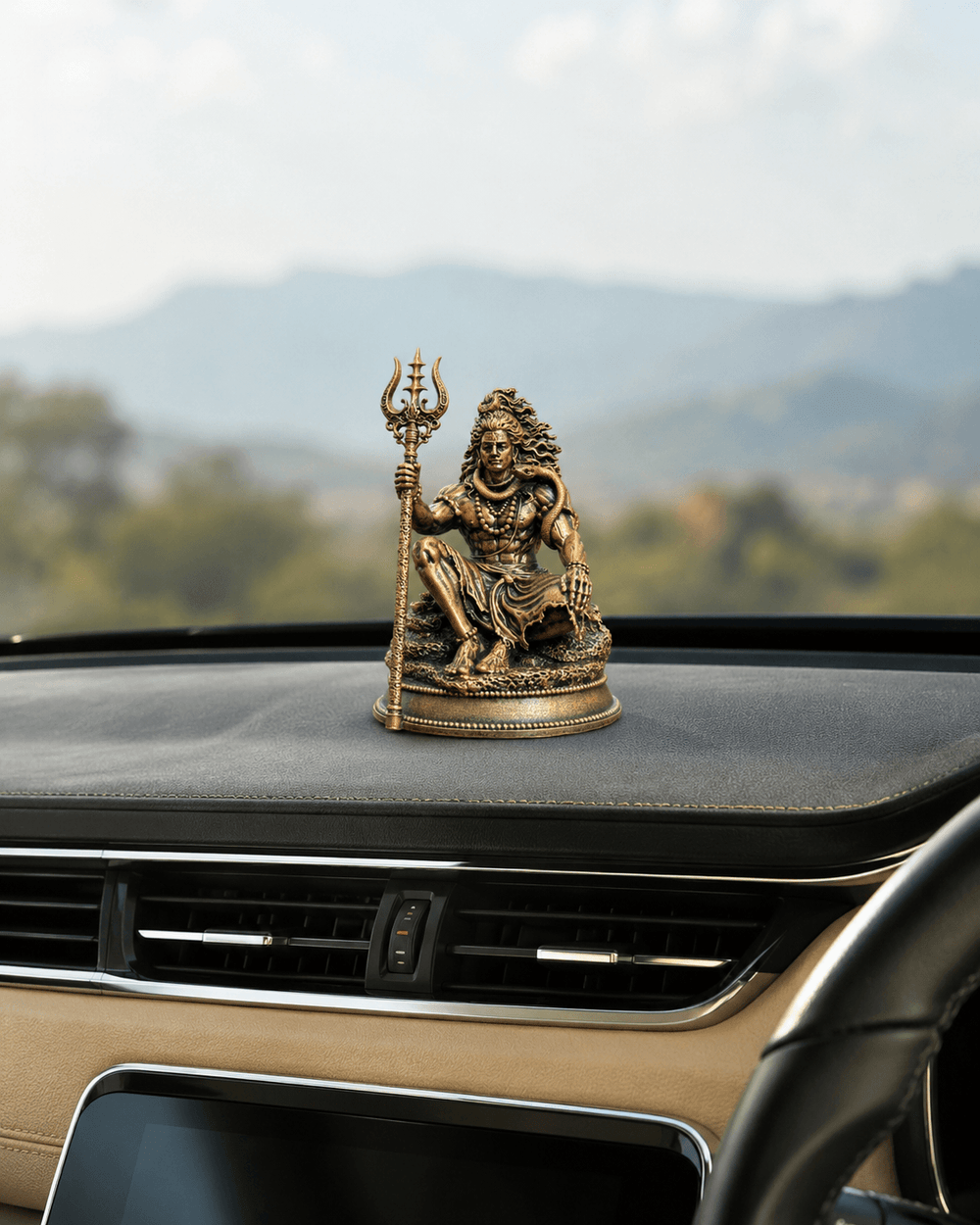The idol on a dashboard with hills beyond the windscreen