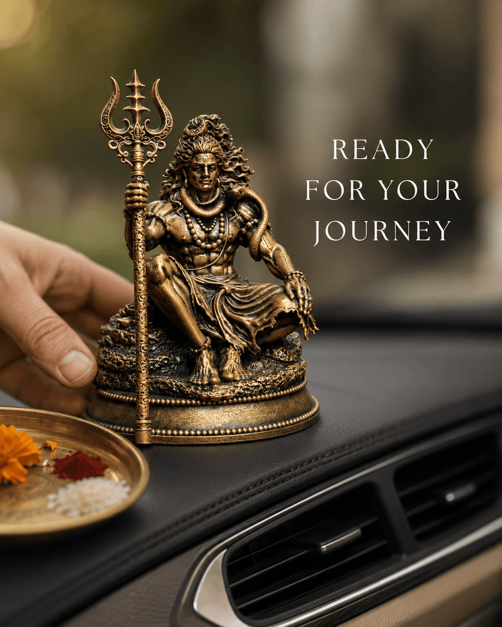 A hand placing the Mahadev idol on a car dashboard