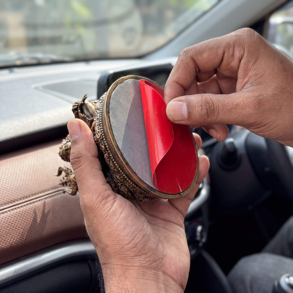 Peeling the red liner off the tape under the idol's base