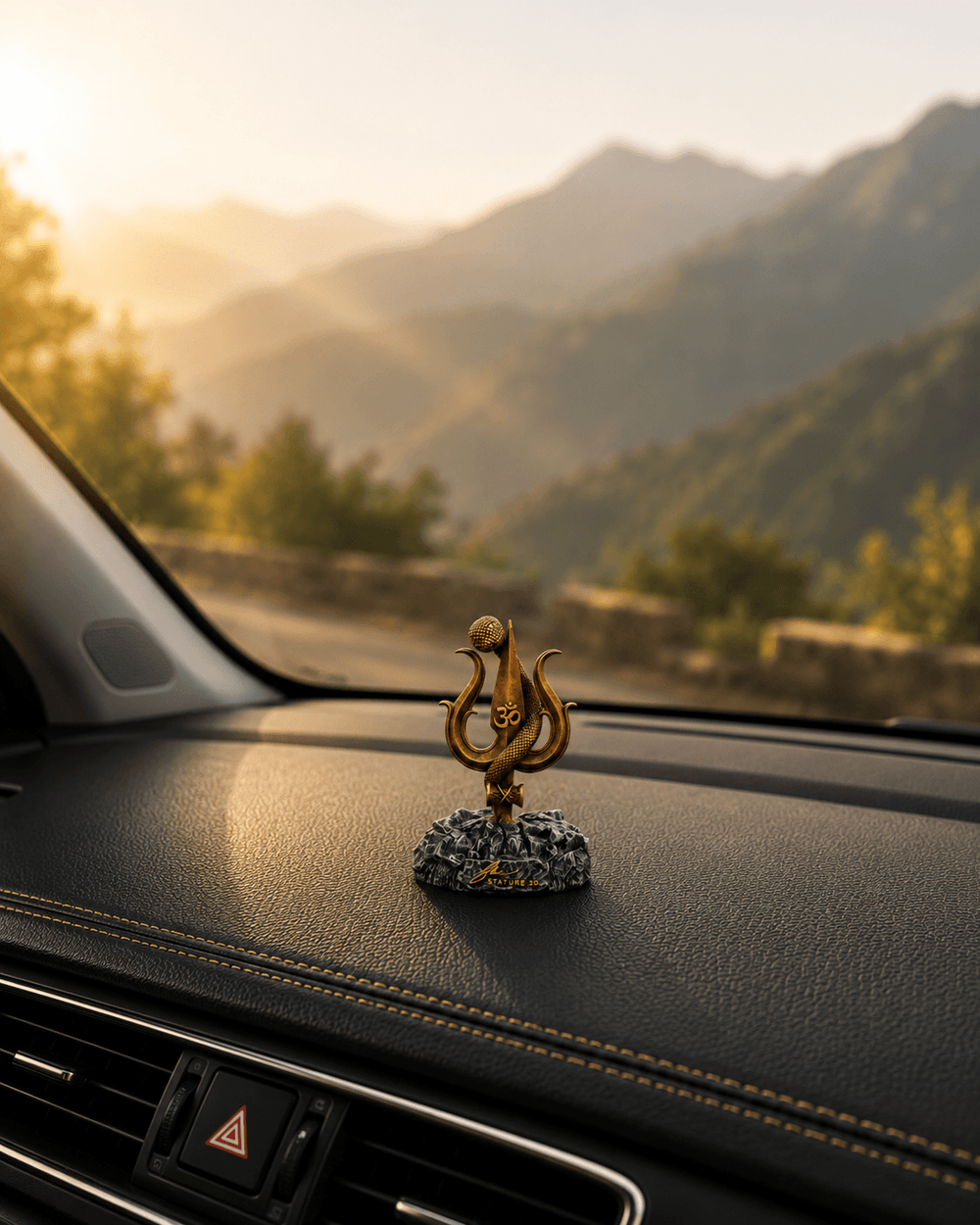 The Shiv Trishul idol on a dashboard with hills beyond the windscreen