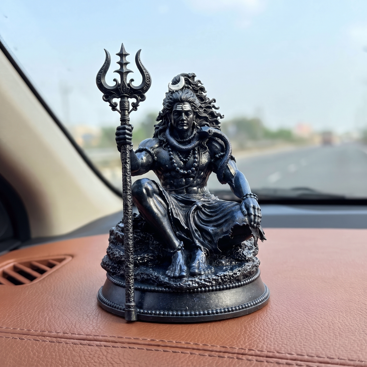 Mahadev Trishul Dhyan Idol, Black Edition — on a car dashboard with the road ahead