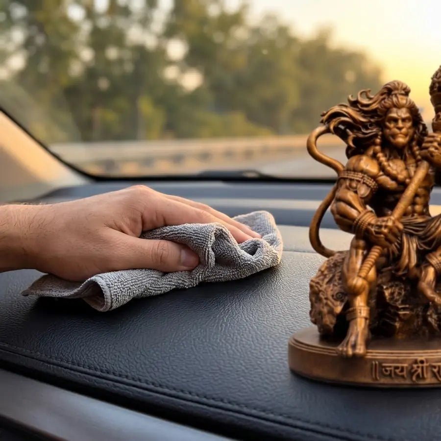 Wiping the car dashboard clean with a microfibre cloth before placing the Mahabali Hanuman idol